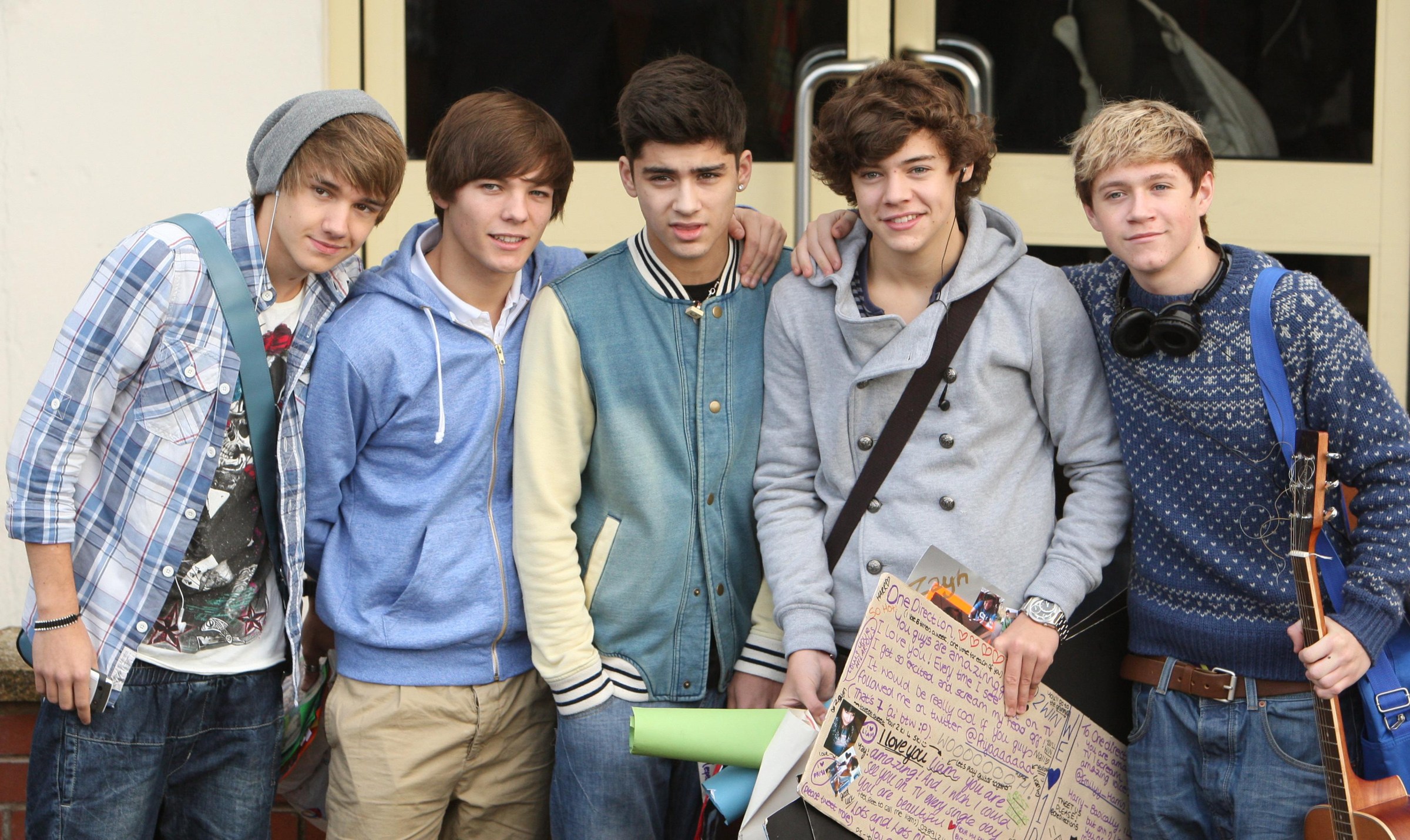 Five young men, one holding a guitar.