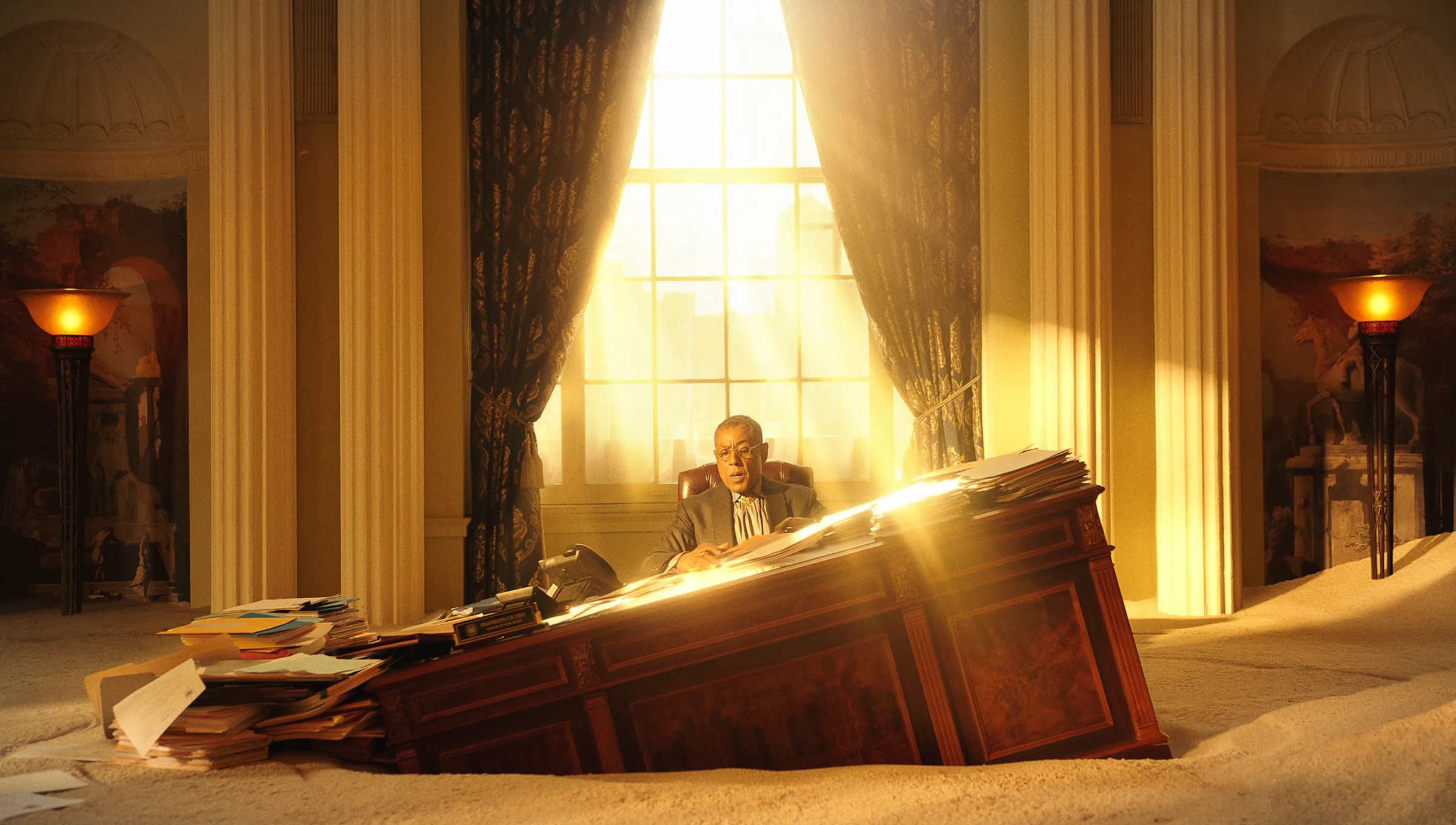 Giancarlo Esposito sitting at a desk in a library sinking and filling up with sand. Light streams in through the window.