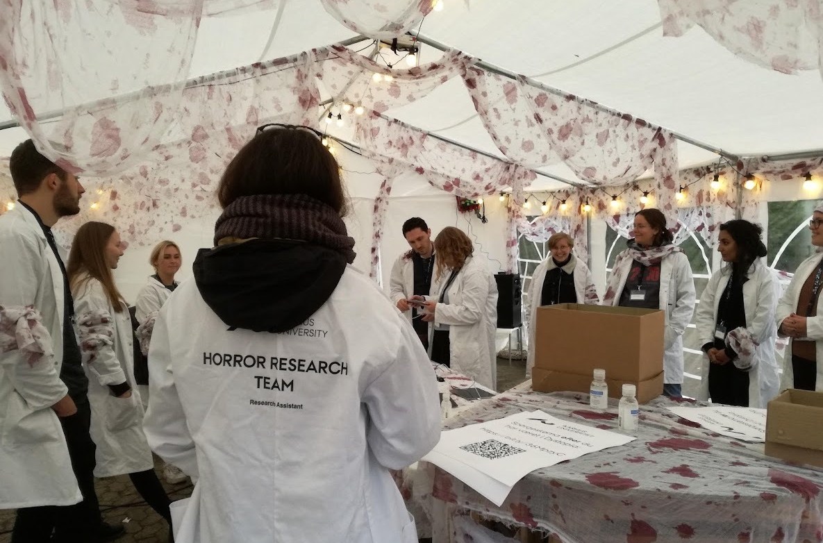 Team members with white coats stand in a decorated tent.