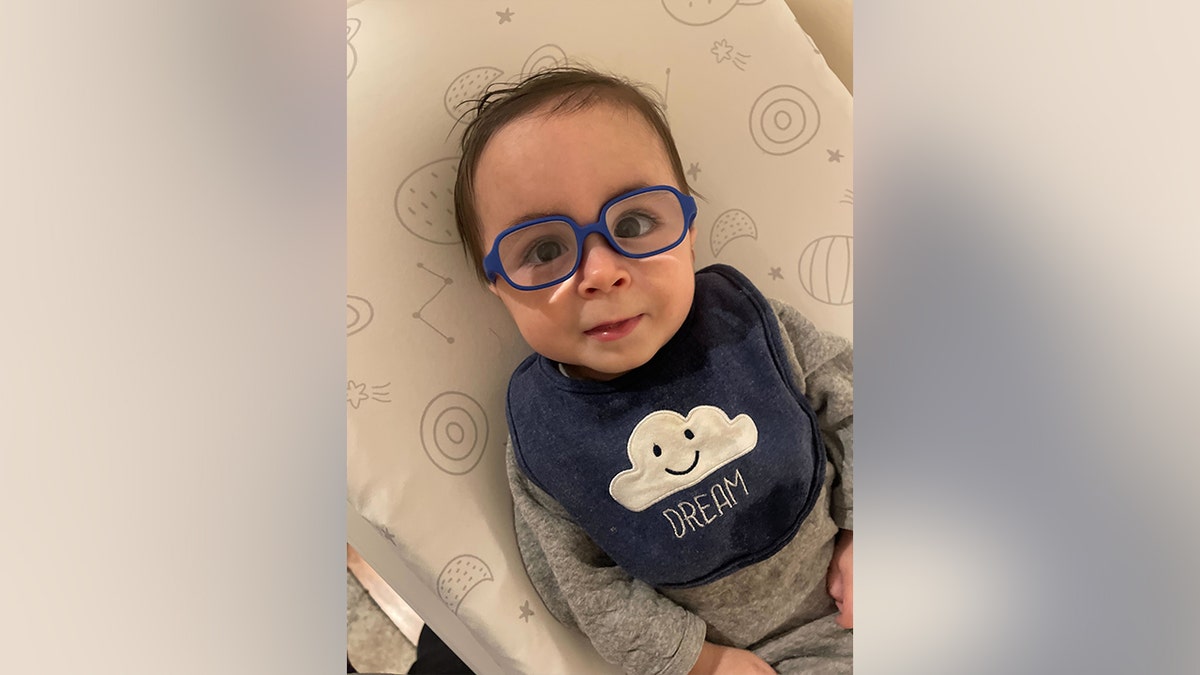 Baby Liam looks up through his glasses on his first day wearing them.