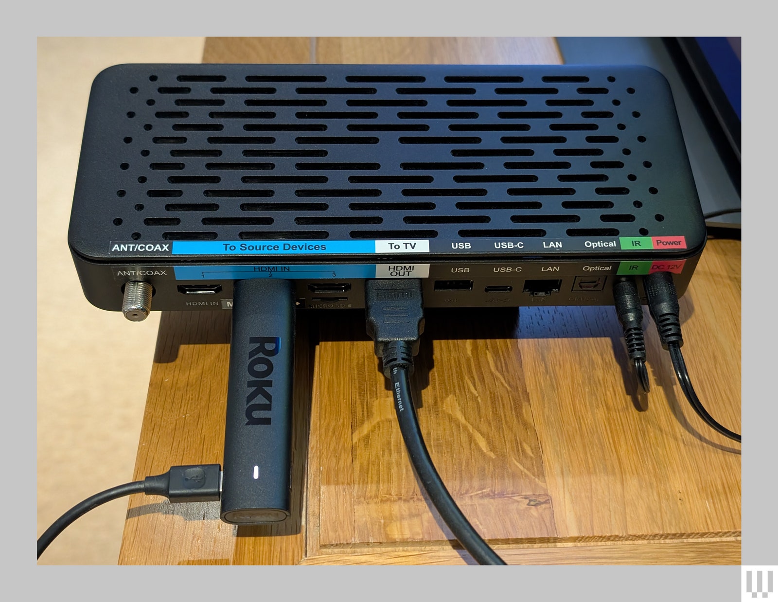 The settop box of the Jubilee TV system a black rectangular device showing the back with plugs and streaming stick for Roku