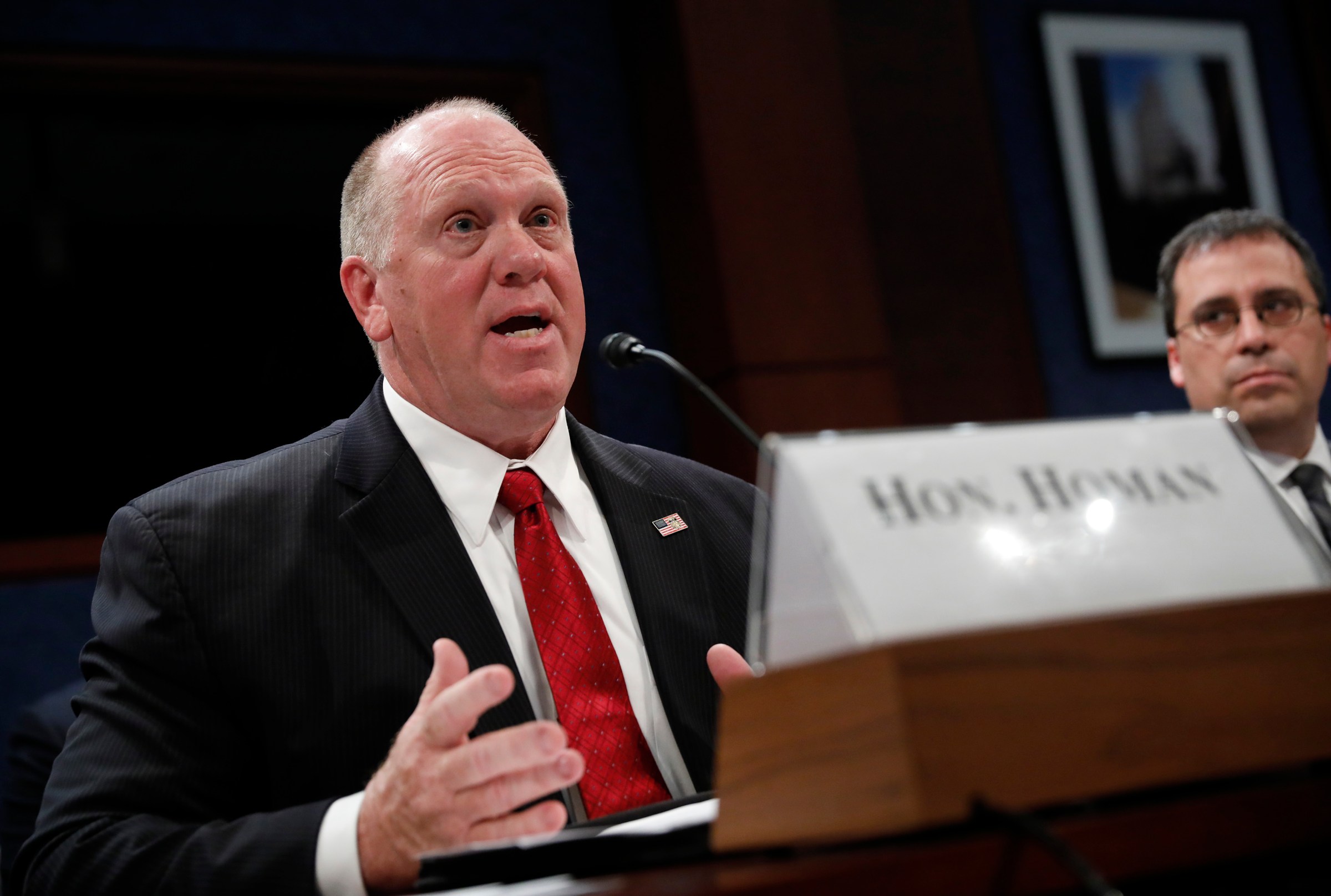 Tom Homan, sitting behind his name plate and speaking.