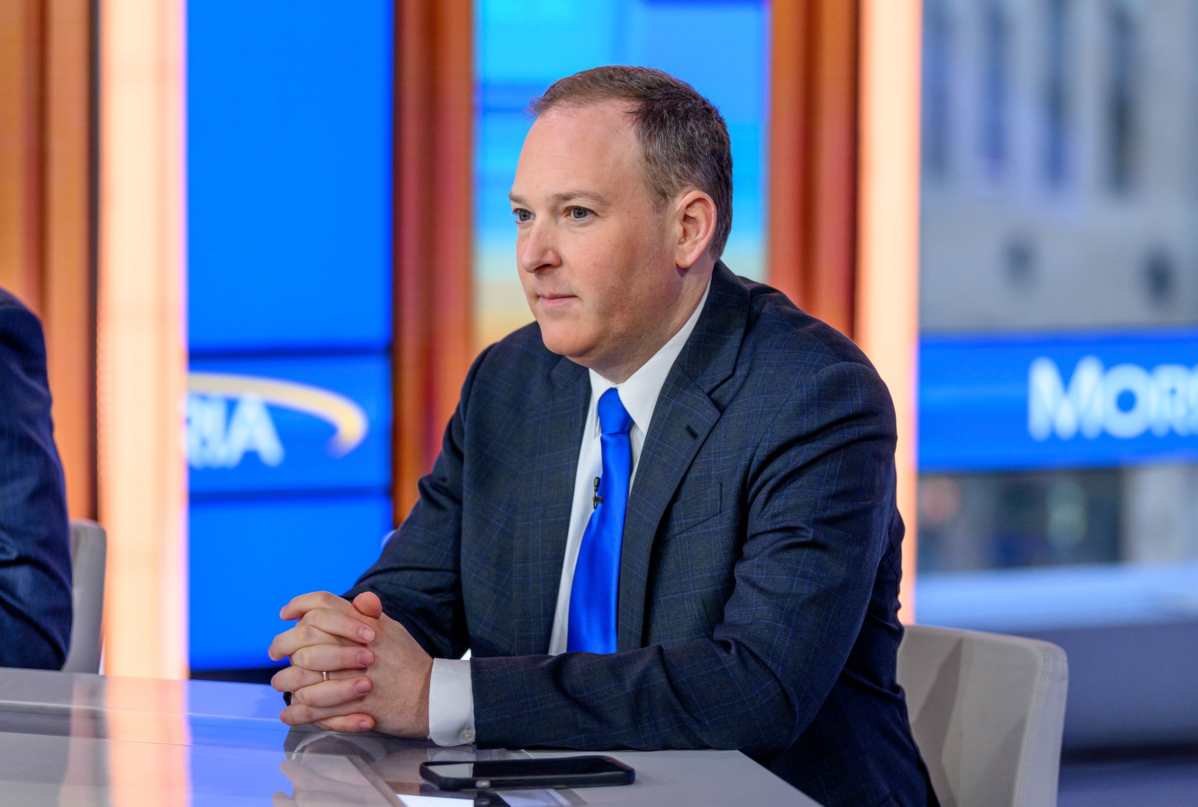 Lee Zeldin sits quietly at a desk with his hands folded.