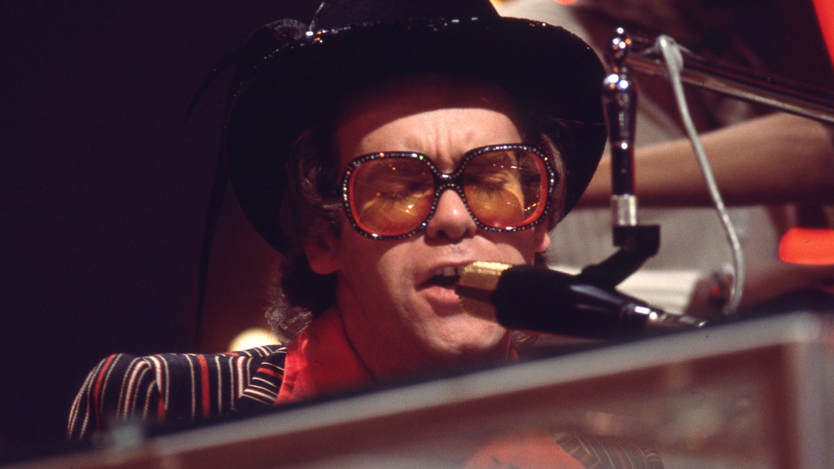 A close-up of Elton John singing in front of a piano