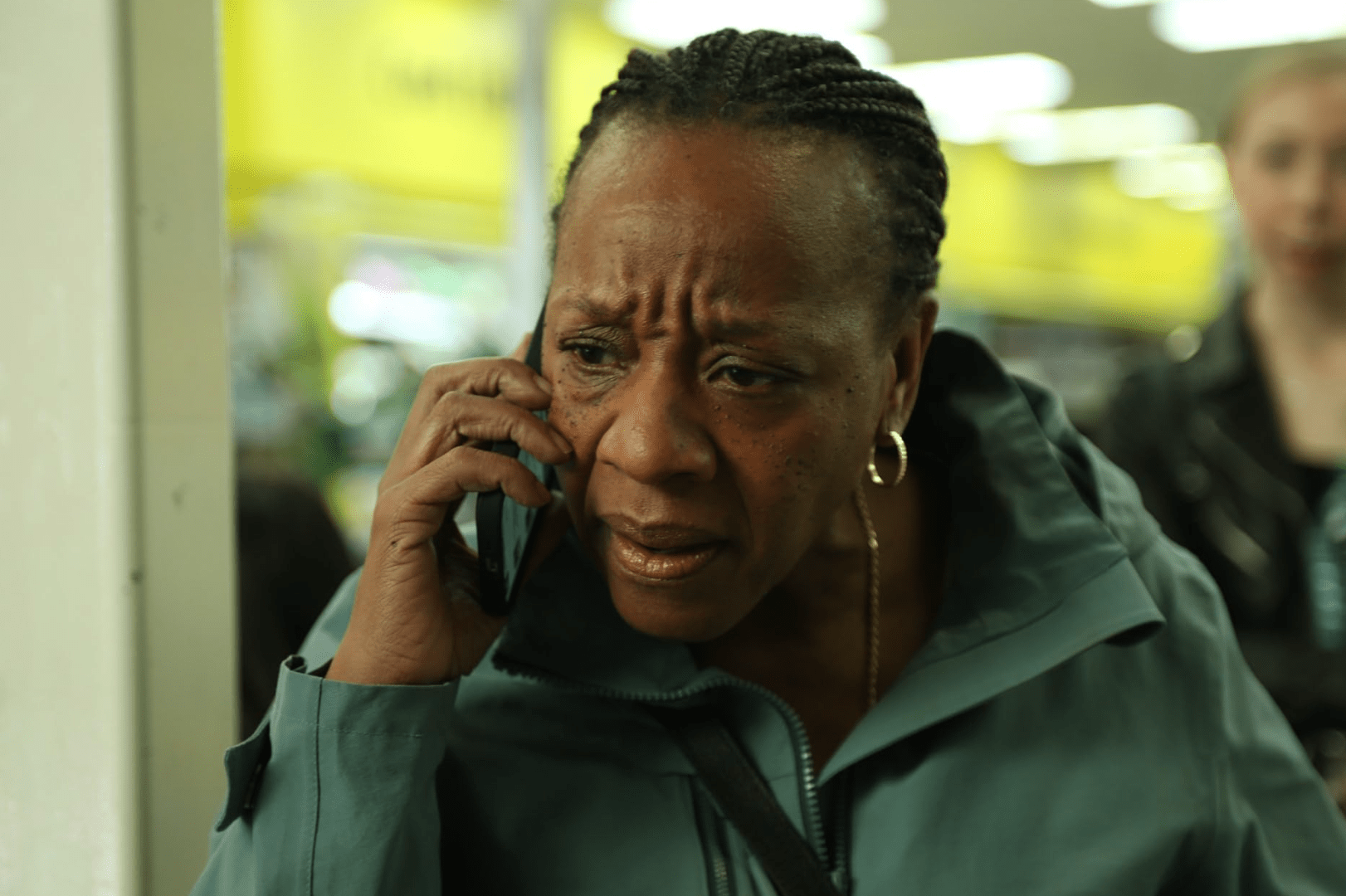 An older Black woman frowns as she holds a phone to her ear.