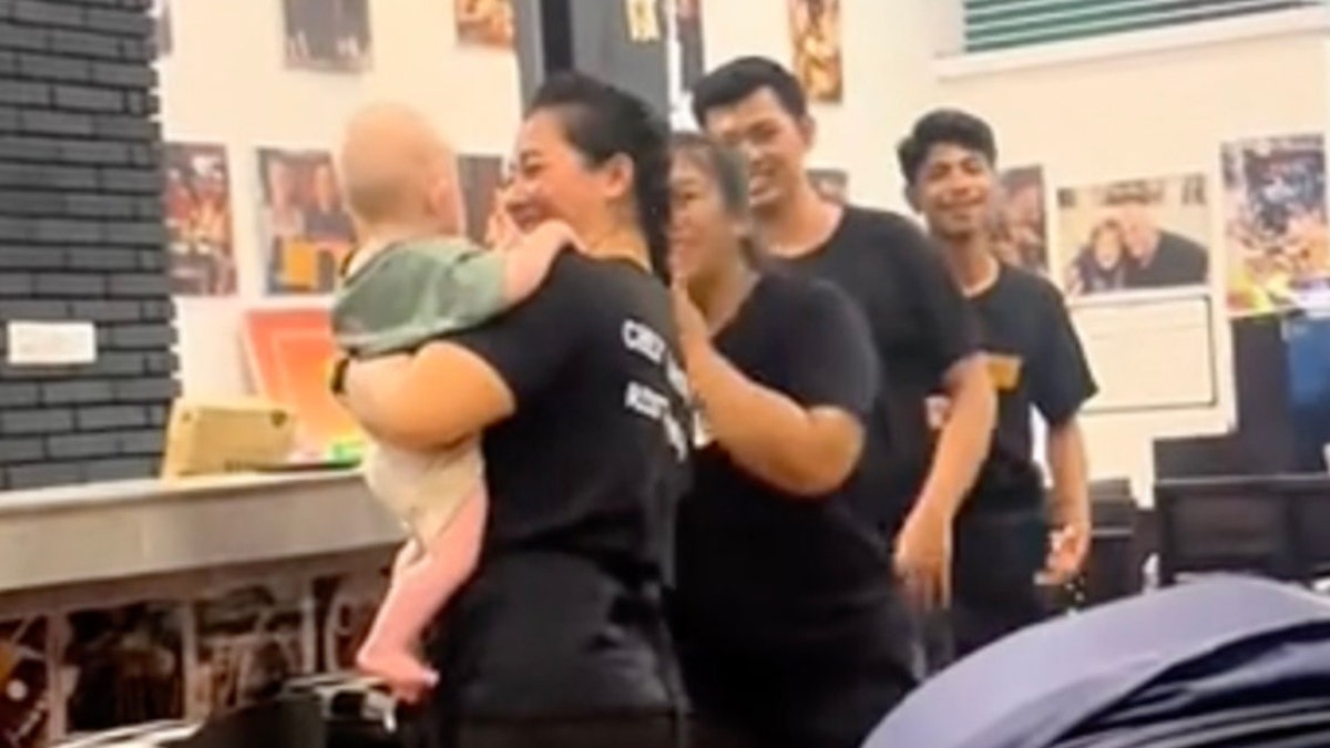 Employees at a restaurant in Bali entertain a baby.