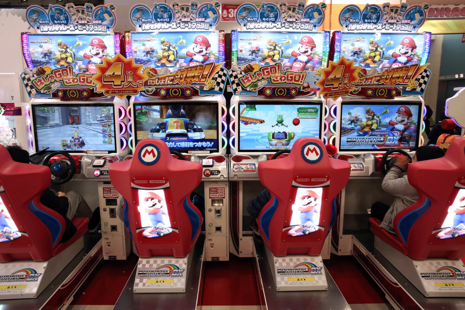 Kids playing mariocart in an arcade