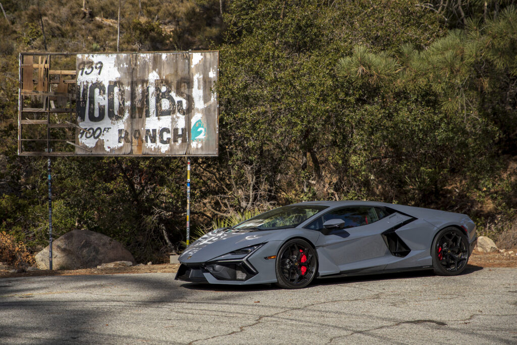 A Lamborghini Revuelto parked next to a dilapidated advertising hoarding.