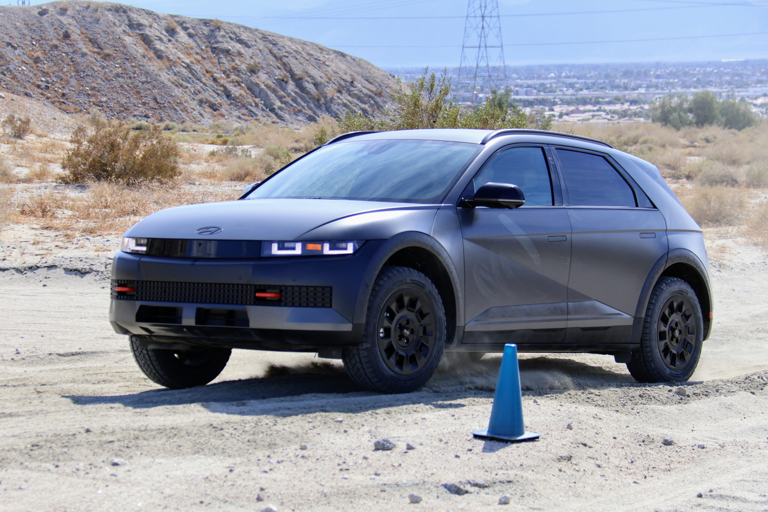A dark grey Ioniq 5 drives on an off-road course