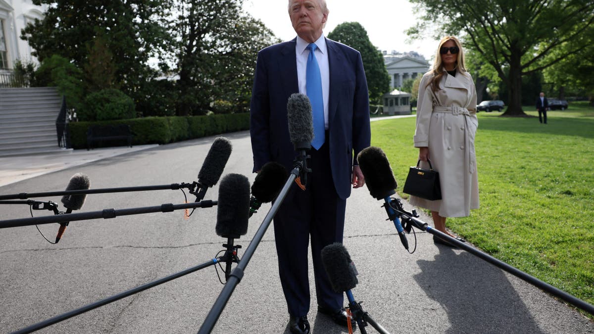 U.S. President Donald Trump speaks to members of the media next to first lady Melania Trump as they depart for Rome, Italy, to attend Pope Francis' funeral, at the White House in Washington, D.C., U.S., April 25, 2025