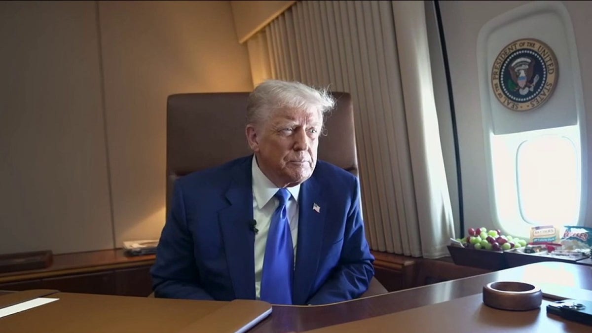President Donald Trump sits in a chair at a desk aboard Air Force One.