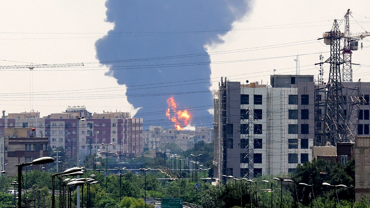 massive plume of smoke and fire rise from a distance in southern Tehran