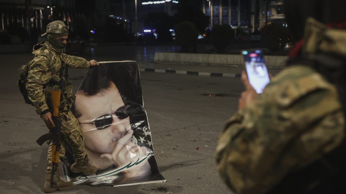 A Syrian opposition fighter takes a picture of a comrade stepping on a portrait of Syrian President Bashar Assad in Aleppo, early Saturday, Nov. 30, 2024. 