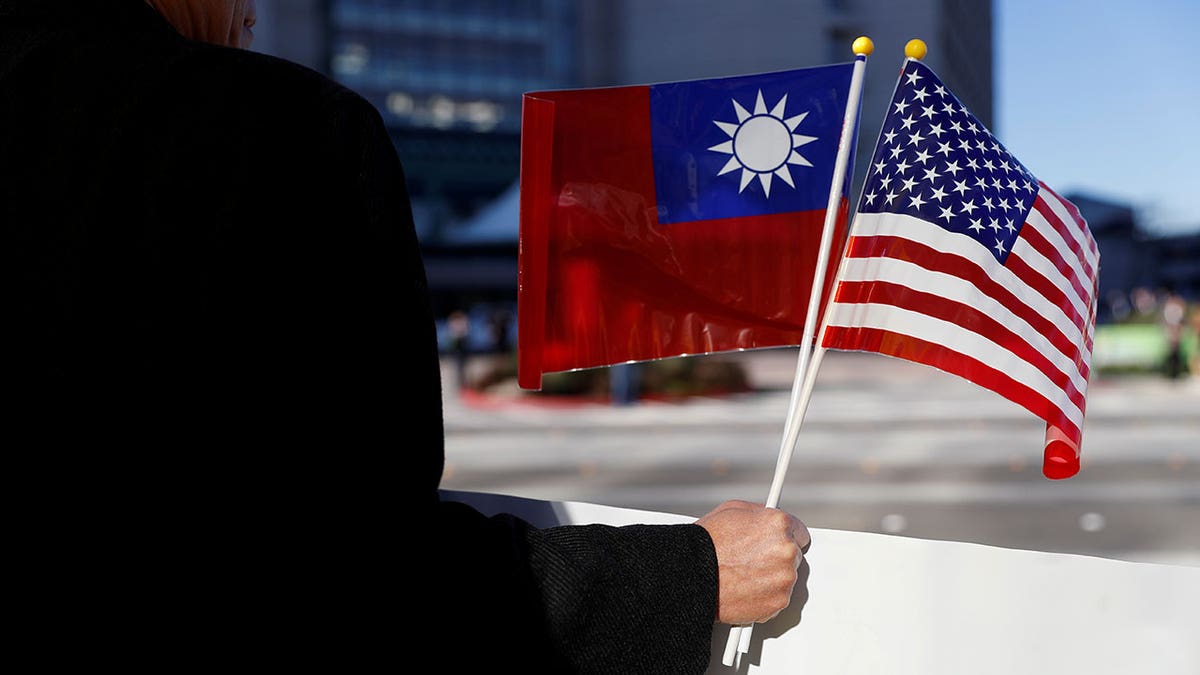 man holding Taiwan, US flags
