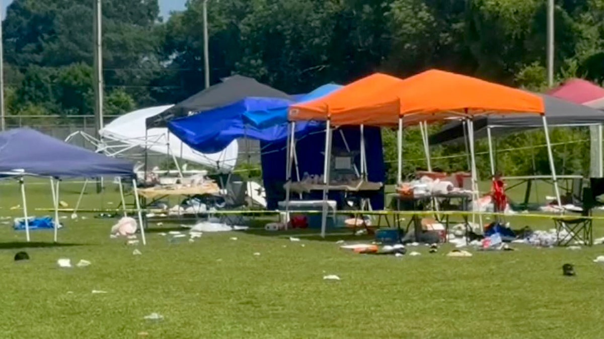 crime scene tape around tents and debris on grass 