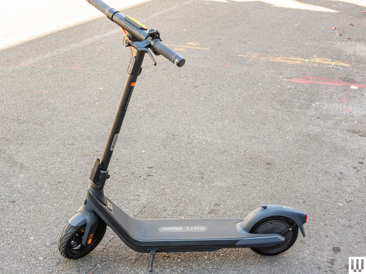 Side view of a Segway E2 Pro, a black electric scooter, parked on concrete