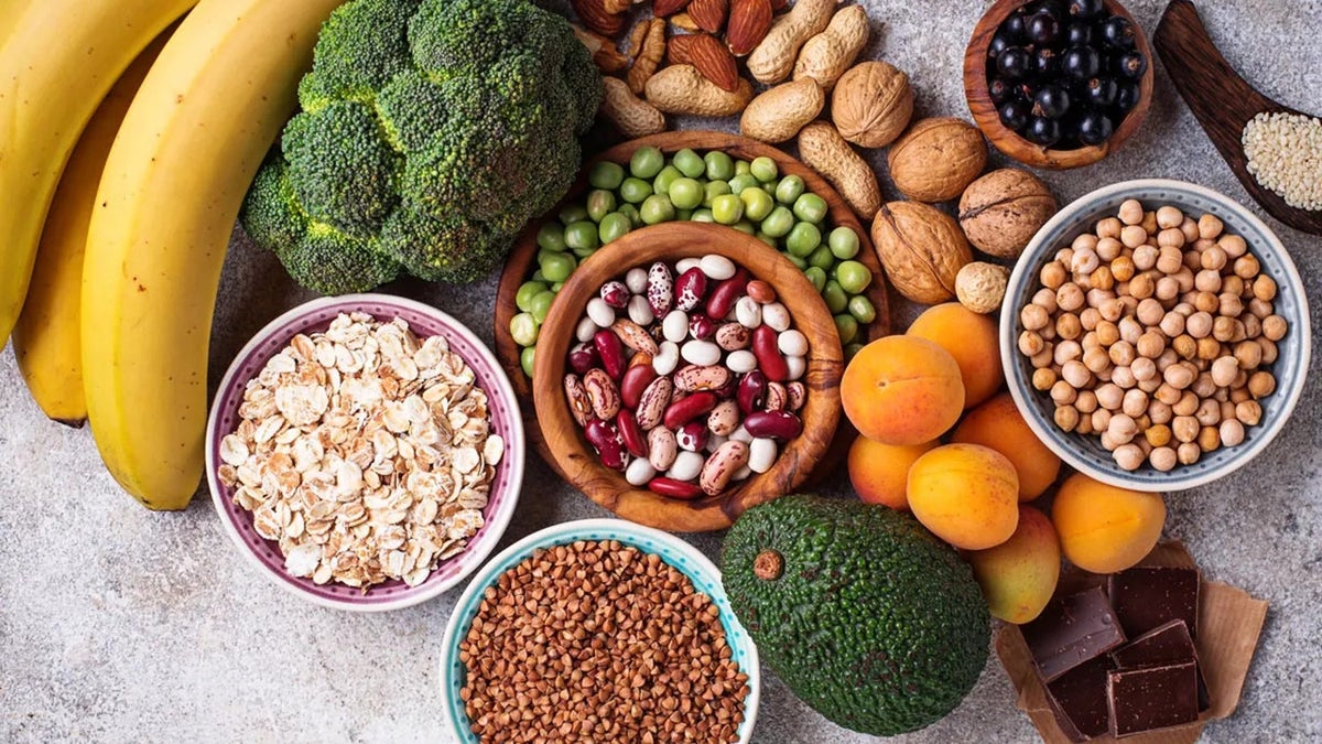 Foods high in magnesium seen on table, including beans, broccoli, apricots and avocado.