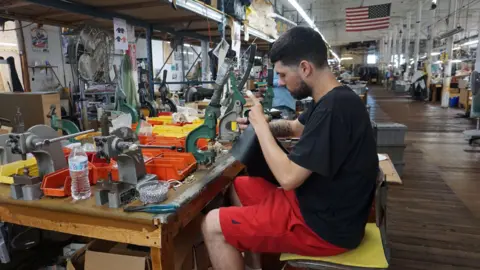 Jared Botelho, a worker at Vanson Leathers, works on snaps for the company's motorcycle jackets