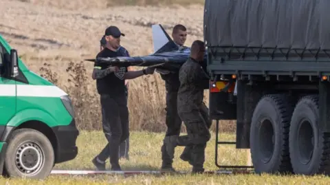 EPA/Shutterstock Polish National Territorial Defense Forces at the crash site of a Russian drone in the village of Wohyn