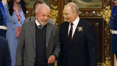 Getty Images Brazil's President Luiz Inácio Lula da Silva and Vladimir Putin walk through a gold-encrusted palace in Moscow, smiling at one another
