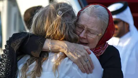 AFP via Getty Images Barbie Reynolds hugs her daughter, Sarah Entwistle, after arriving in Qatar