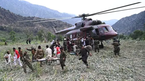 Getty Images Rescuers load an earthquake survivor onto a helicopter