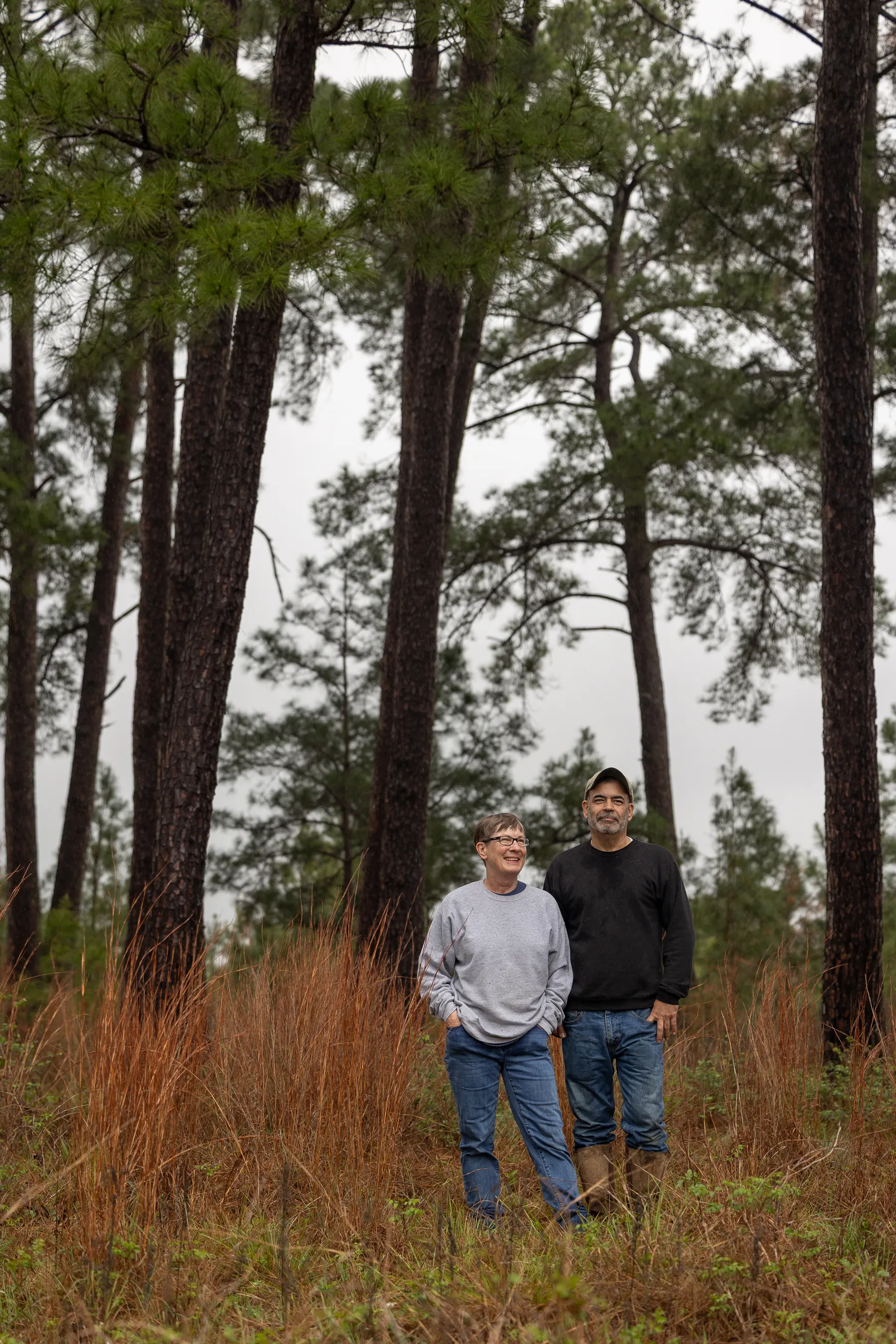 An older couple stand in a meadow on their property