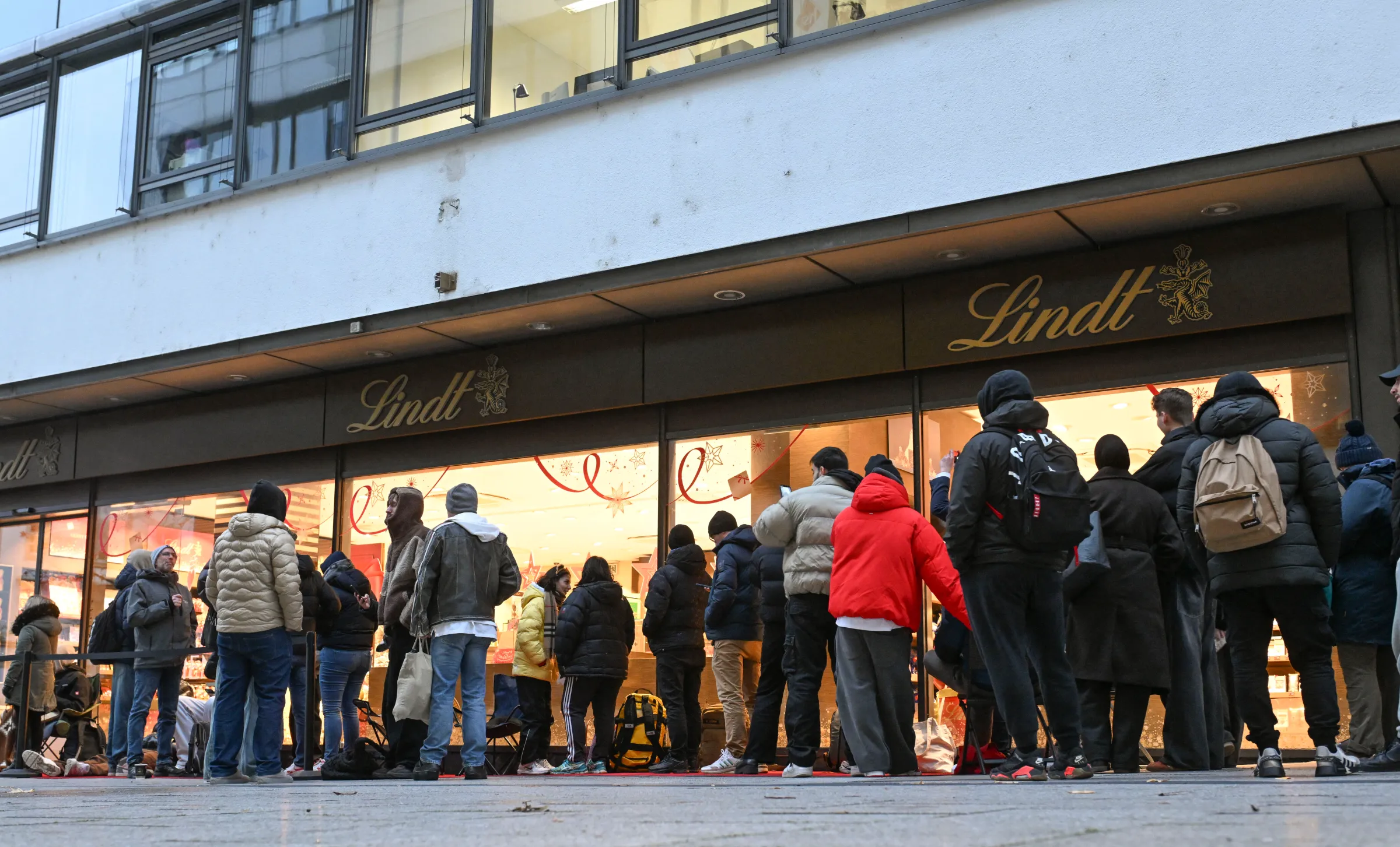 A line of customers stands in front of a Lindt store.