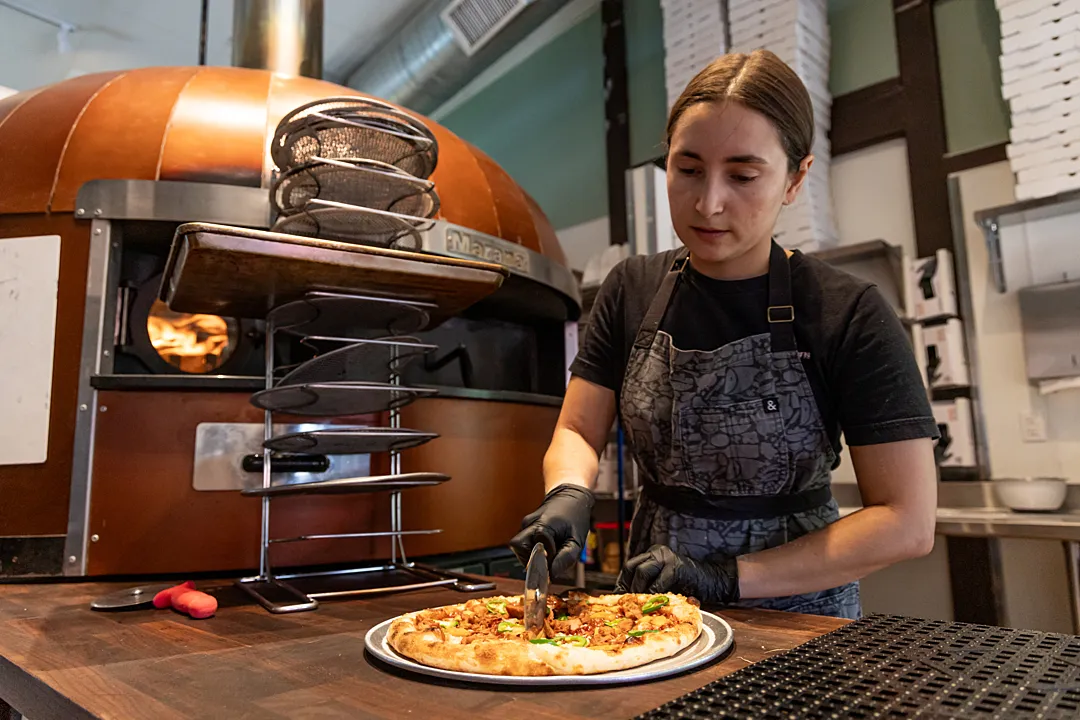 A sous-chef slicing into plant-based pizza