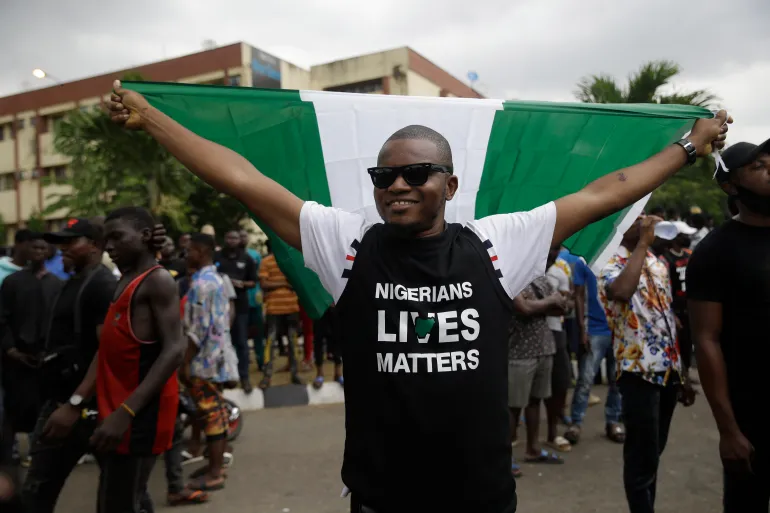 A man holds a Nigerian flag as he demonstrate on the street to protest against police brutality in Lagos, Nigeria, Friday Oct. 16, 2020. Nigerian protests against police brutality continued Friday for the ninth day, with demonstrators fending off attacks from gangs suspected to be backed by the police, warnings from the Nigerian military, and a government order to stop because of COVID-19. (AP Photo/Sunday Alamba)