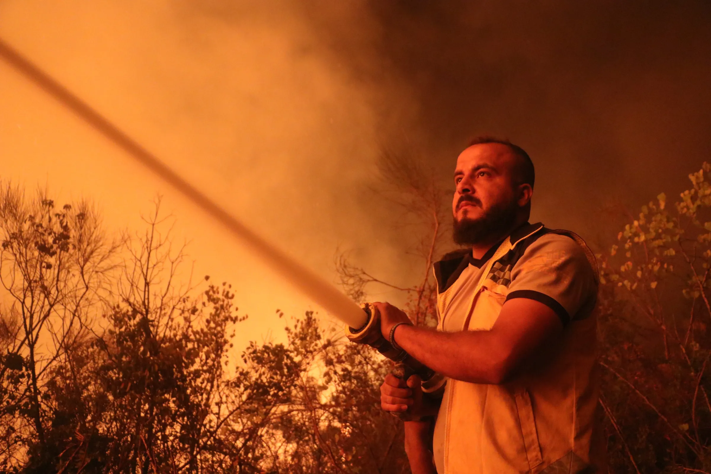 A man holds a fire hose that is spraying water.