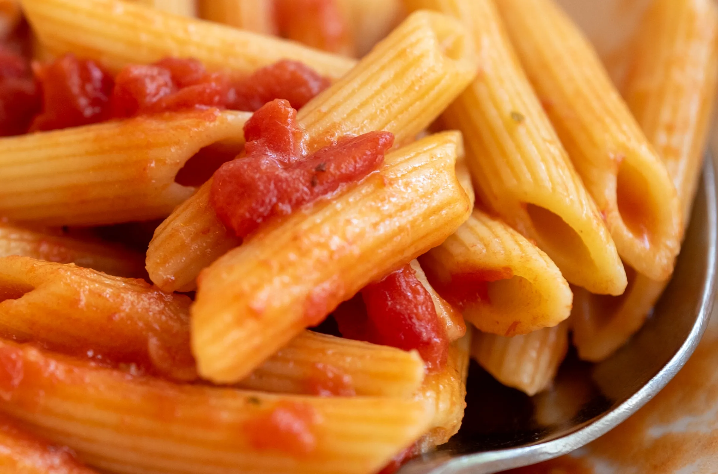 Close-up on cooked penne in red sauce