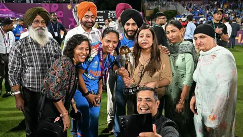 PUNIT PARANJPE/AFP via Getty Images India's captain Harmanpreet Kaur (C) poses with her family members after winning the ICC Women's Cricket World Cup 2025 one-day international (ODI) final match between India and South Africa at the DY Patil Stadium in Navi Mumbai on November 3, 2025. (Photo by Punit PARANJPE / AFP) / -- IMAGE RESTRICTED TO EDITORIAL USE - STRICTLY NO COMMERCIAL USE -- (Photo by PUNIT PARANJPE/AFP via Getty Images)