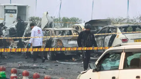 REUTERS/Adnan Abidi Security personnel and a member of the forensic team work at the site of an explosion near the historic Red Fort in the old quarters of Delhi, India, November 11, 2025. 