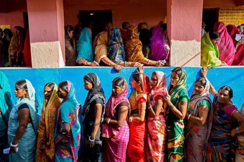 AFP via Getty Images) TOPSHOT - Women voters stand in queues to cast their ballots at a polling station during the first phase of voting for assembly elections on November 6, 2025, at the Raghopur constituency in the Vaishali district of the Indian state of Bihar. (Photo by Sachin KUMAR / AFP) (Photo by SACHIN KUMAR/AFP via Getty Images)
