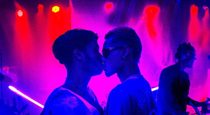 Two young latino men kissing at a club