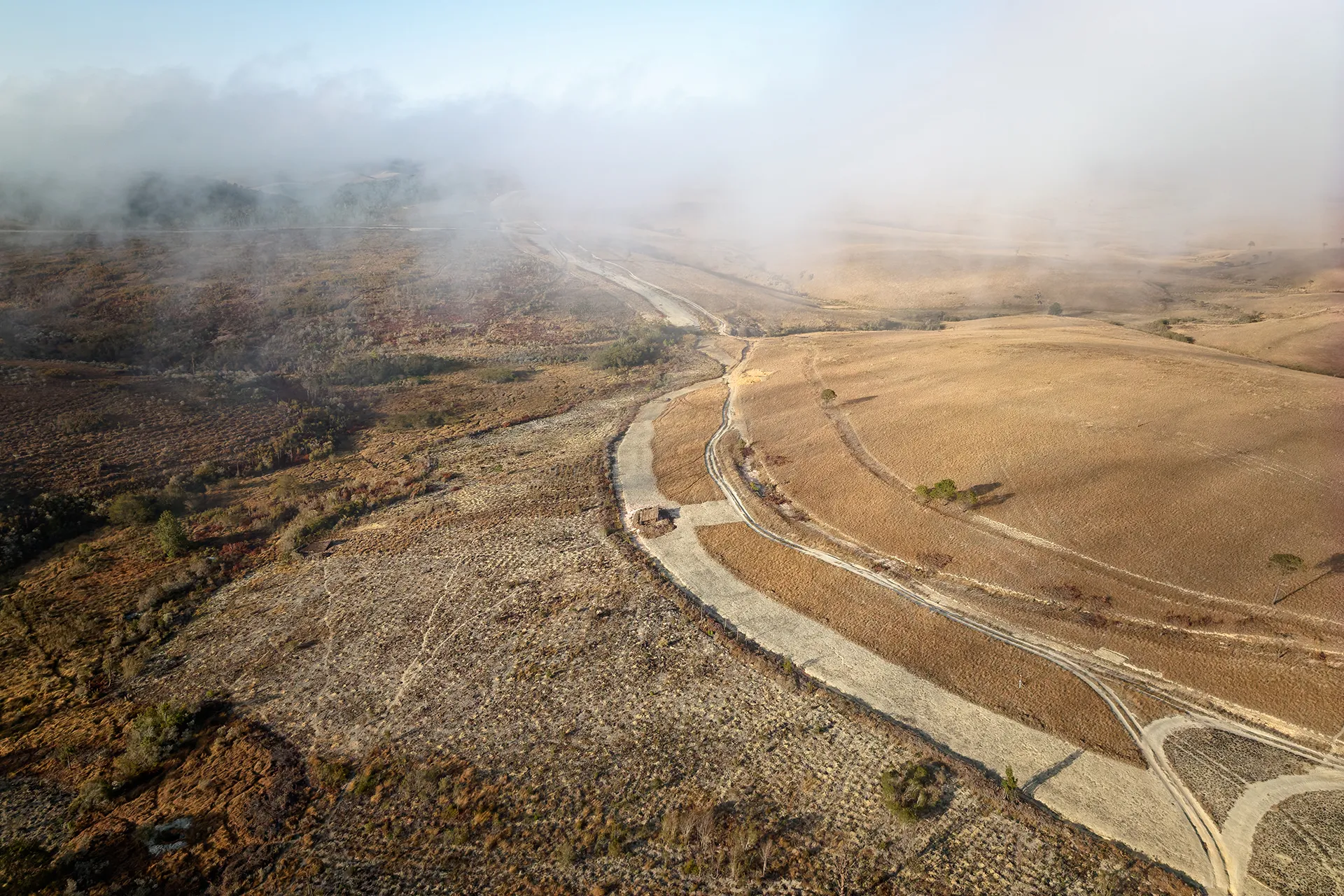 Brown grasslands are clouded by smoke in the distance.