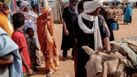 AFP via Getty Images Men, women and children are seen at a refugee camp in Mauritania, with their livestock (7 June 2022)