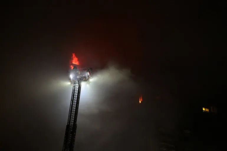 A firefighters works at the scene, after a started fire burning bamboo scaffolding across multiple buildings