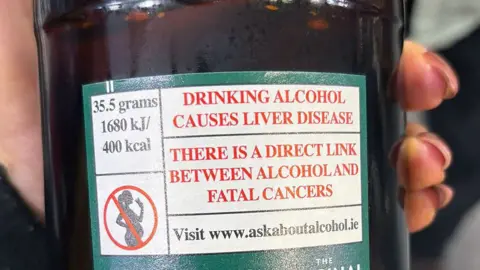 Alcohol causes liver disease and cancers warning label on the back of a bottle of cider