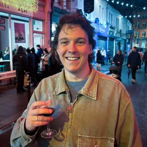 Jack standing in the street with a glass of wine in his hand