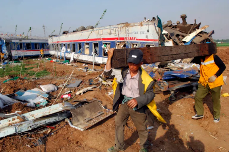 epa01328085 Two railway workers carry a sleeper at the site where two passenger trains collided near Zibo, east China's Shandong province, 28 April 2008. The Qingdao to Beijing- bound train derailed after colliding with the Yantai to Xuzhou train in the early hours of 28 April. According to the Chinese Ministry of Railways, the accident has caused 66 deaths and 247 people are injured and receiving treatment in various medical facilities in the Zibo city area. EPA/NG KONG