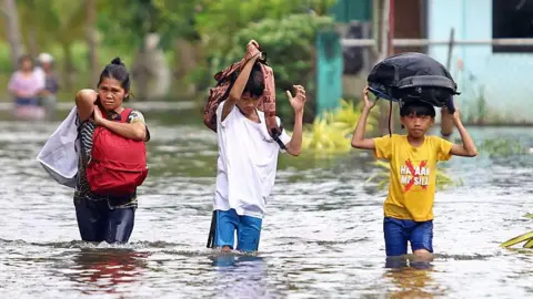 AFP via Getty Images Residents evacuate from their flooded homes due to heavy rain brought by Typhoon Fung-wong in Remedios T Romualdez, on the southern island of Mindanao on November 8, 2025