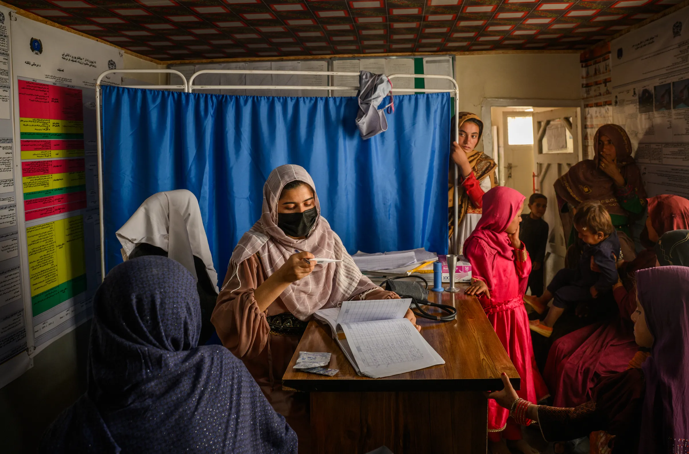A midwife measures the temperature of a woman in Afghanistan at a small clinic for woman and children that recently reopened after being closed due to USAID cuts.