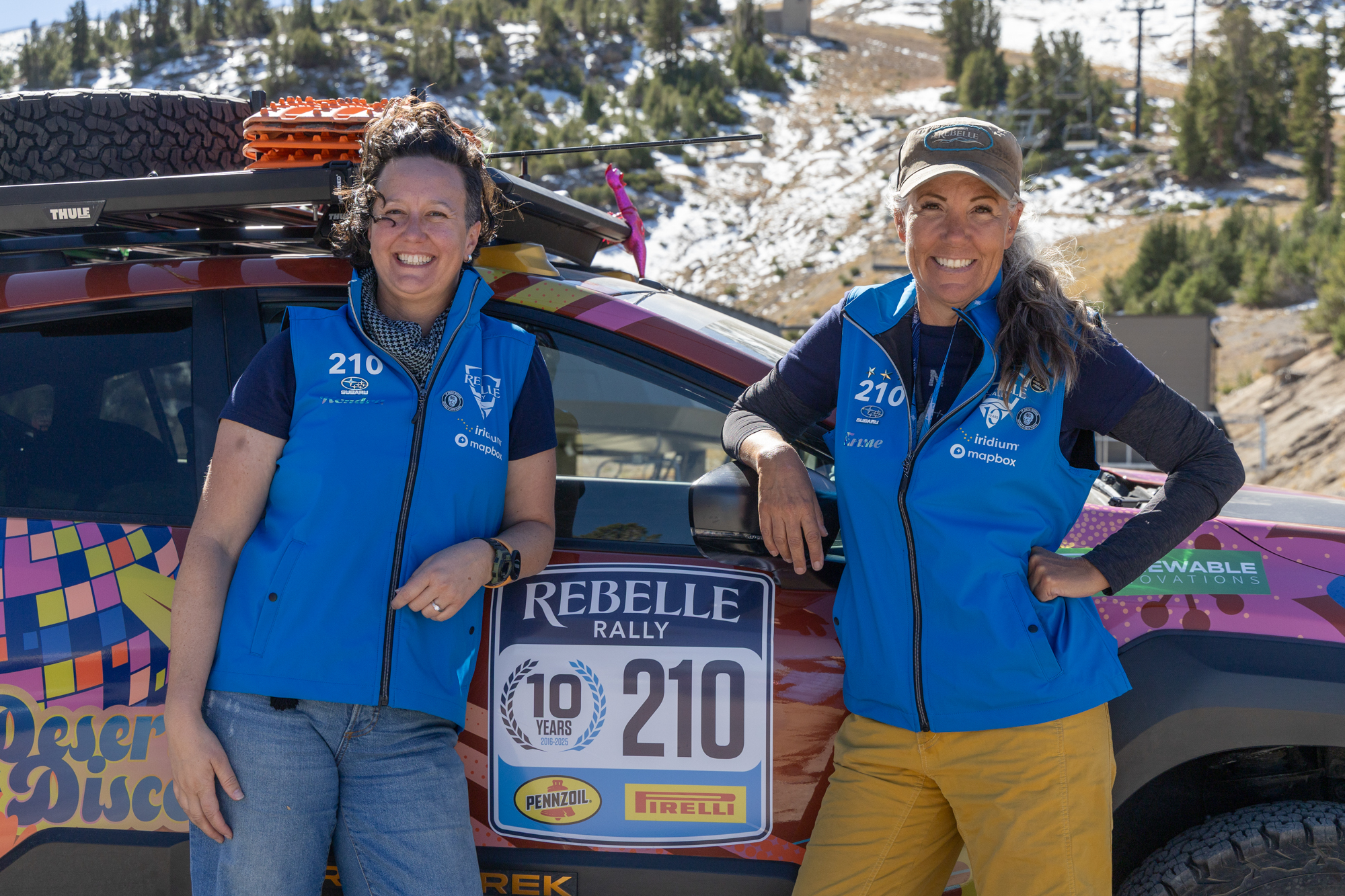 Two women rally drivers stand in front of their car