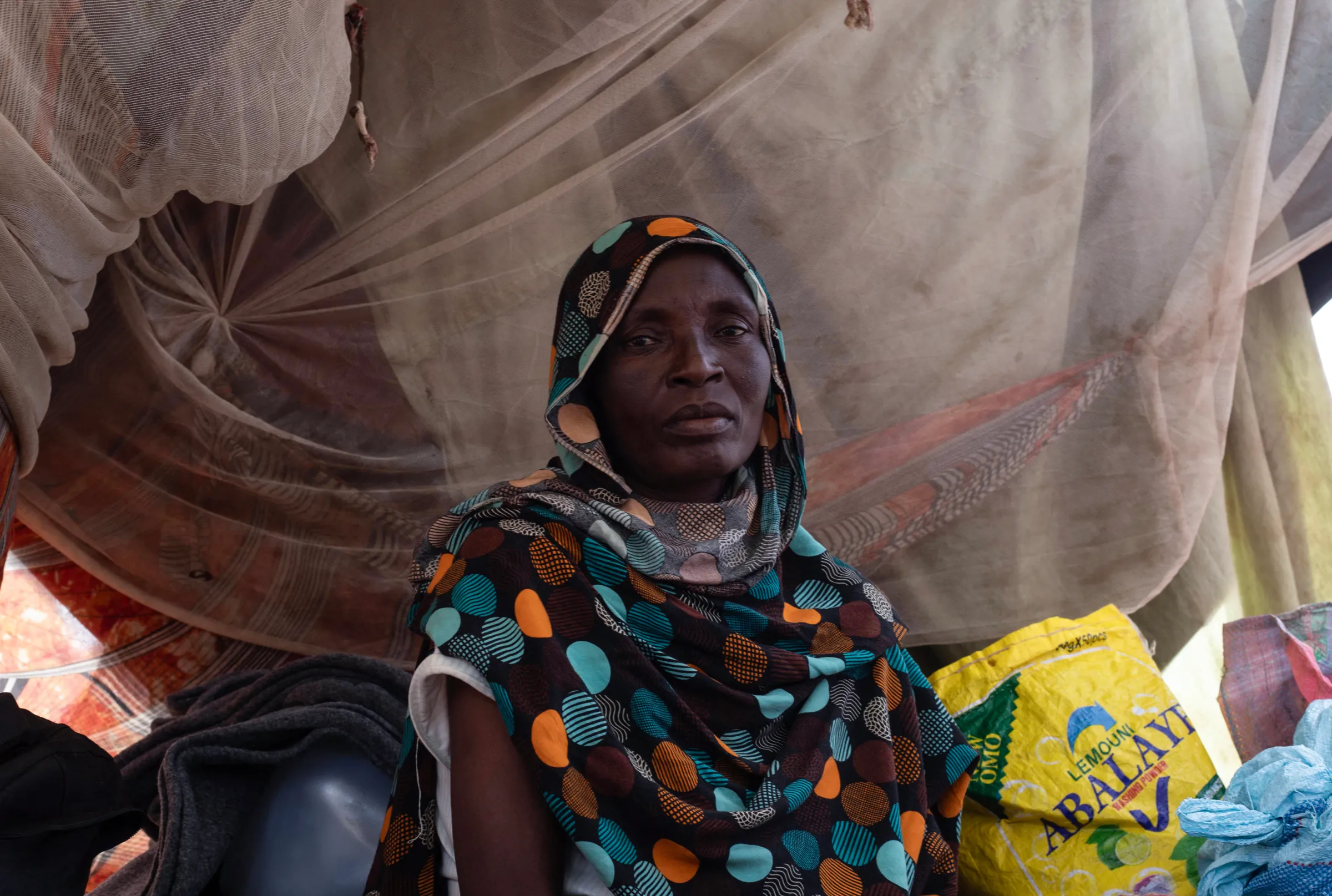 A woman sits in a makeshift tent