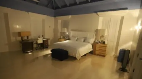 US Congress A bedroom with hardwood floors with a bed with white covers and white walls