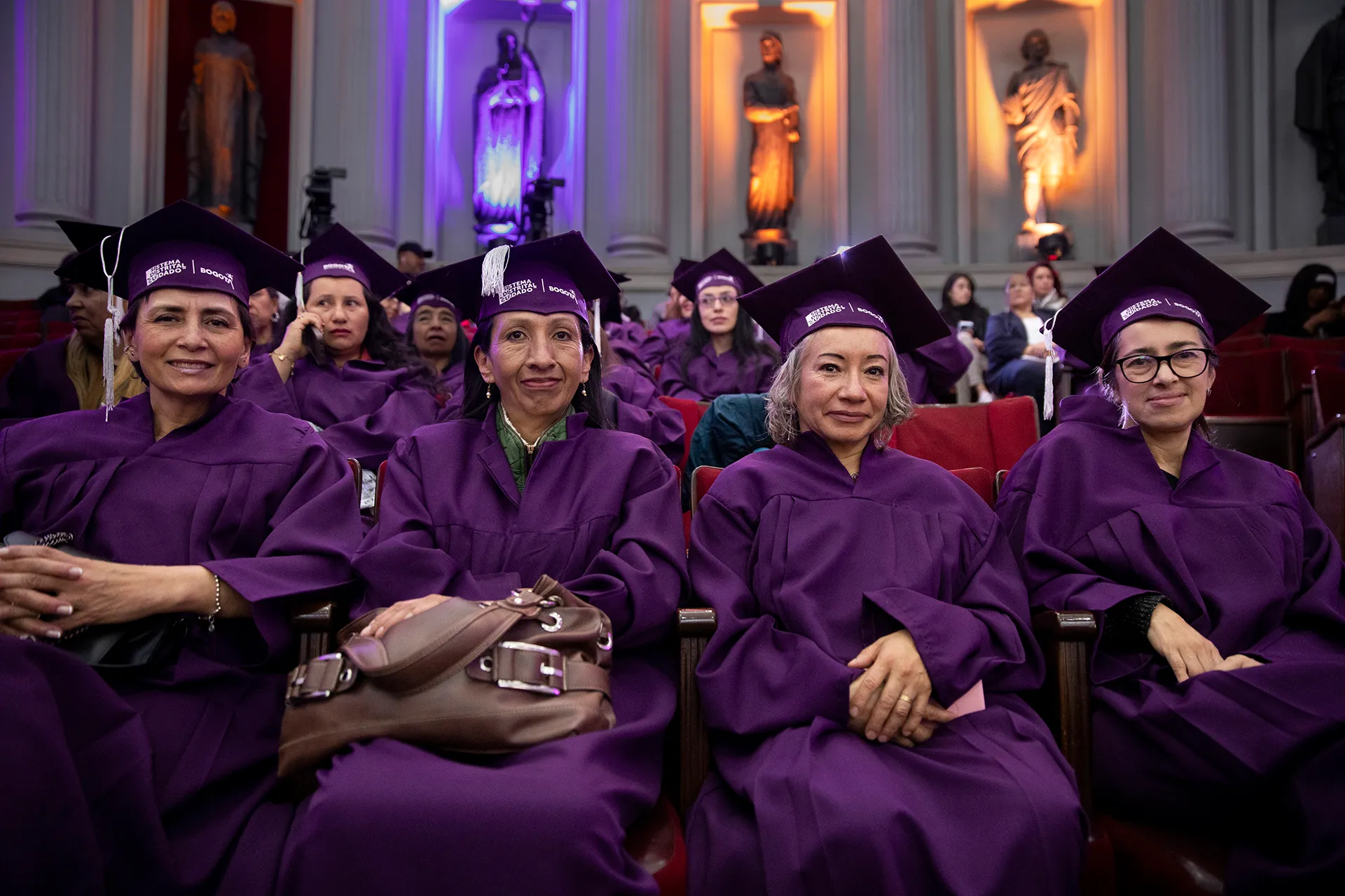 A crowd of women attending a graduation ceremony, all wearing purple caps and gowns