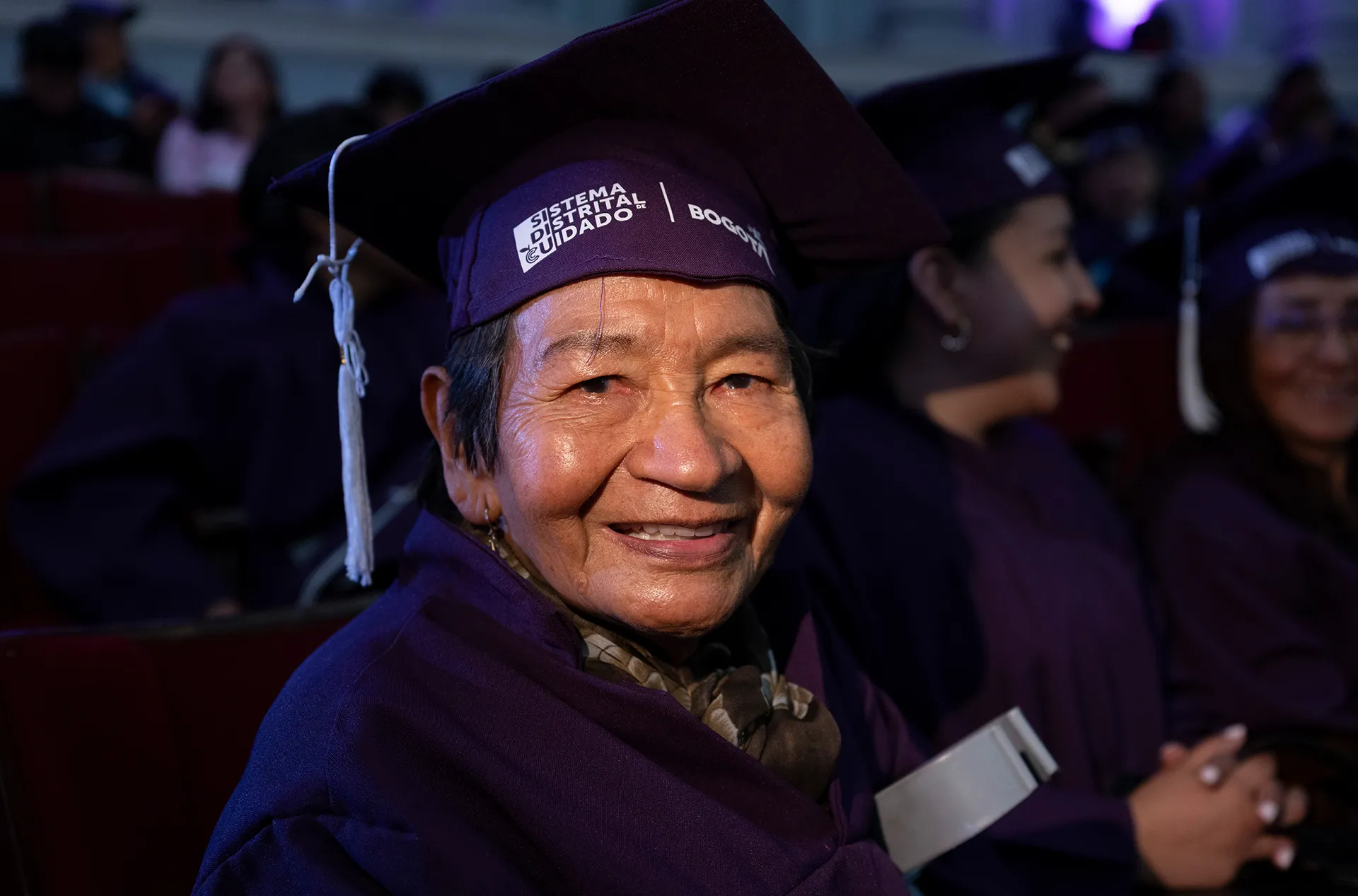 a woman smiles in a purple graduation cap and gown