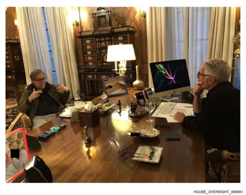 House Oversight Committee Bannon pictured at a desk speaking with Epstein. 